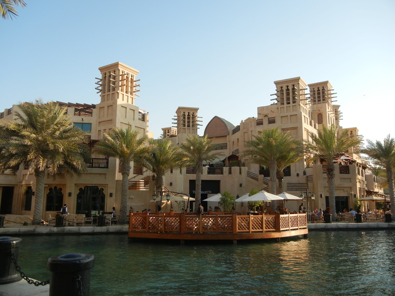 canal, outdoors, architecture, building, dubai, incidental people, sky, tree, building exterior, water, clear sky, mall, city, nautical vessel, mode of transportation