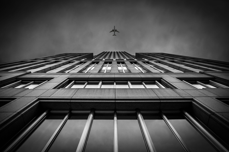 airplane, skyscraper, city, sky, building, windows, building exterior, directly below, window, low angle photography, perspective, day, outdoors