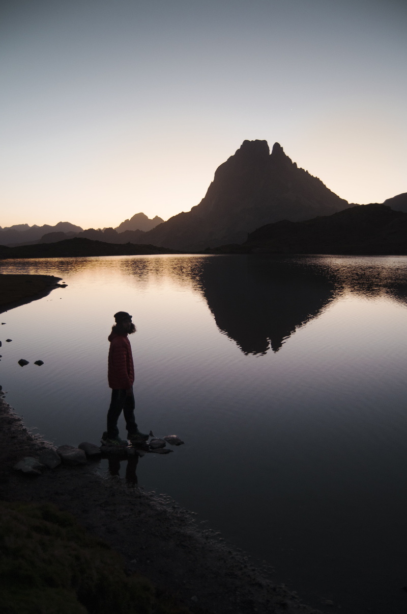 water, solitude, person, dawn, man, near, beauty in nature, adventure, wanderer, rock, real people, alone, beside, explorer, sky, tranquility, mountain range