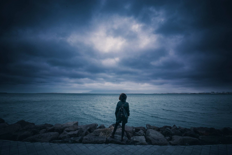 leisure activity, sea, standing, female, person, water, shore, clouds, ocean, young, roadside, back, full length, land, looking, nature, lifestyles, stones
