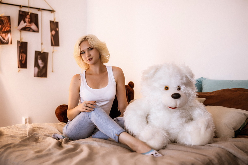 depth of field, bed, blonde, jeans, looking at viewer, teddy bears, portrait, sitting, women, bedroom, 1080P, indoors, model, in bed, women indoors, tank