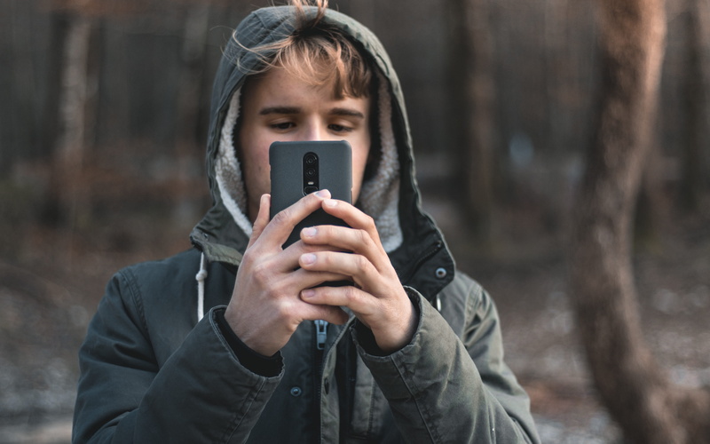 5K, focus on foreground, holding, smart phone, leisure activity, portrait, portable information device, clothing, connection, phone, activity, outdoors
