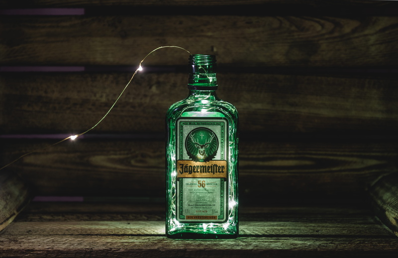 lights, focus on foreground, food and drink, text, communication, single object, still life, no people, jagermeister, green color, table, 5K, indoors