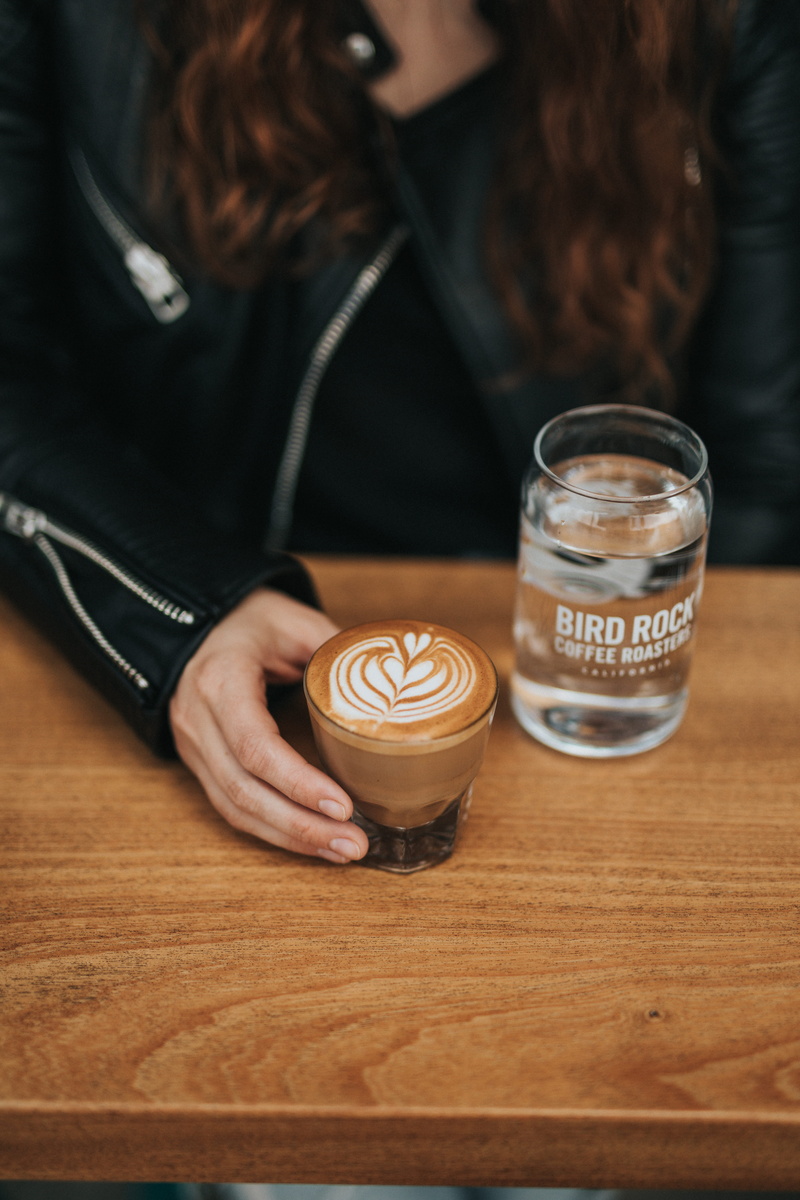 coffee - drink, coffee lover, coffee fiend, latte art, cappuccino, wooden table, hairstyle, mocha, beside, one person, coffee roaster, hand, person, macchiato
