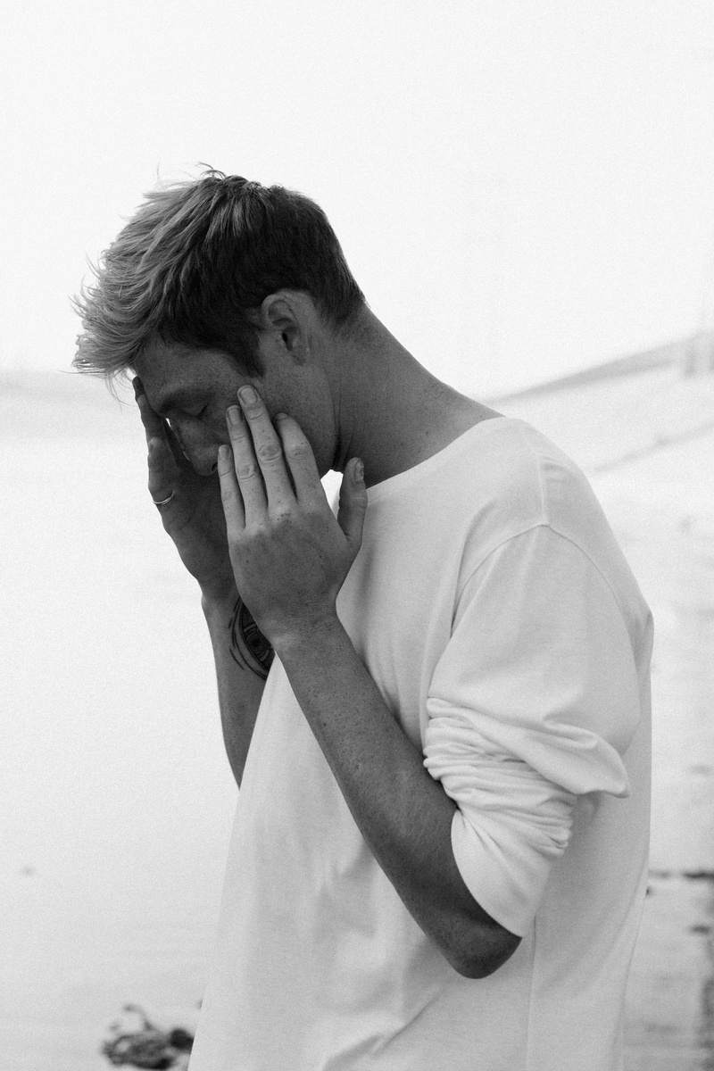 grayscale, young adult, holding, day, portrait, casual clothing, waist up, face, sand, standing, human face, emotion, covering, young men, contemplation
