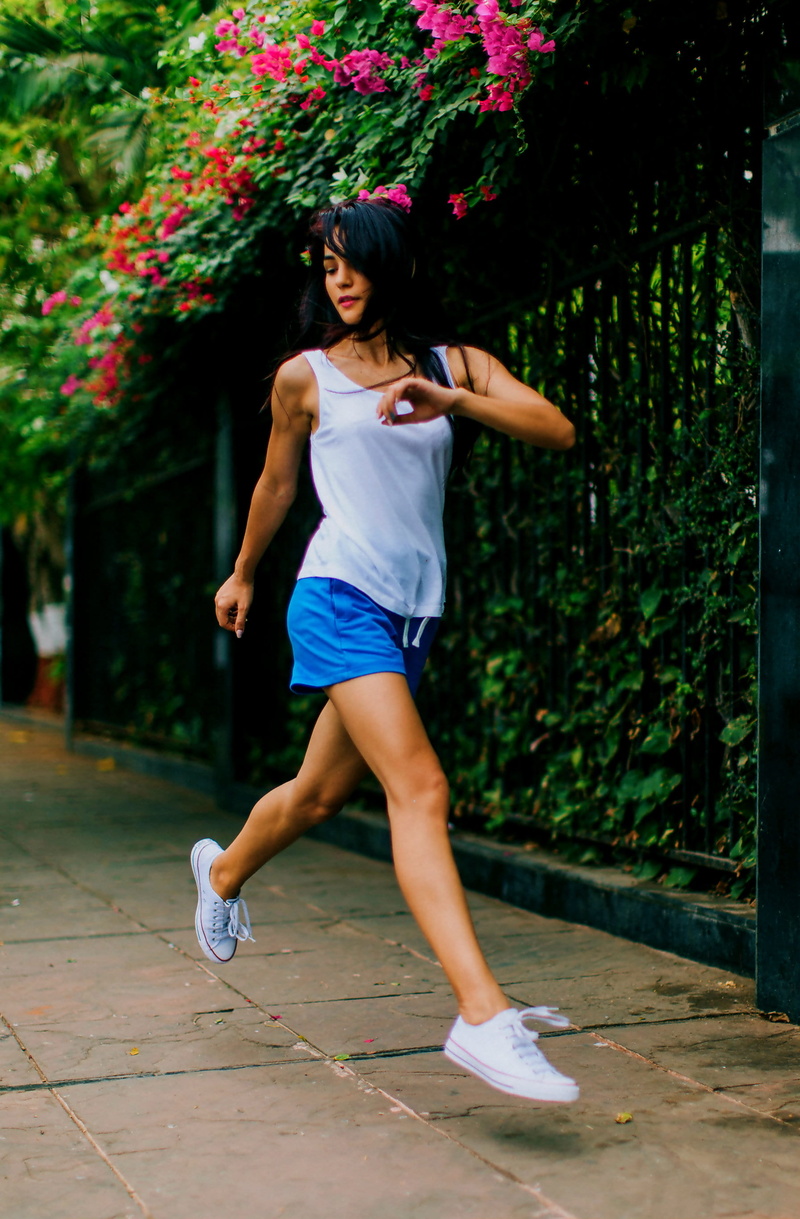 front view, tank, petaled, black, beautiful woman, jumping, run, real people, ground, pink, teenager, metal, plant, street, blue, female, outdoors, near