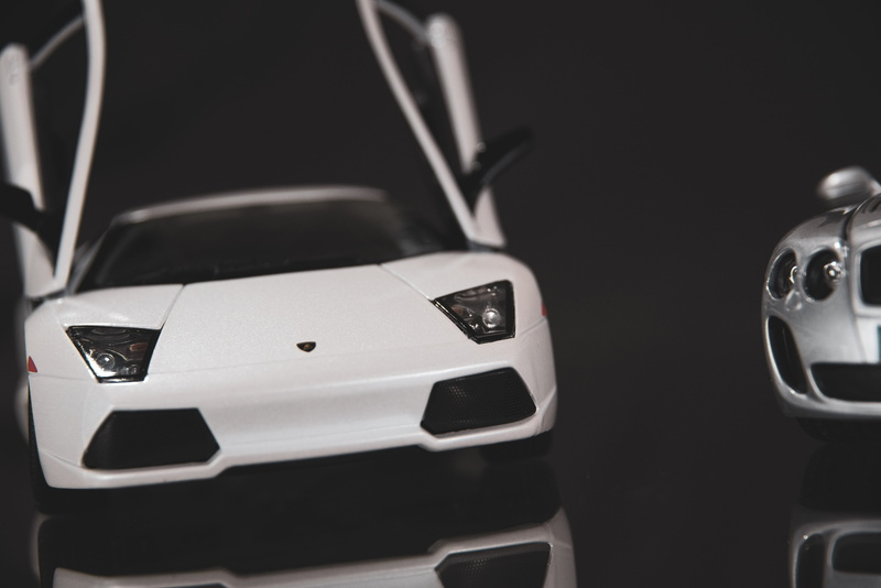 focus on foreground, bumper, toy, alloy wheel, cell phone, mobile phone, still life, car, wheel, transportation, studio shot, close-up, car wheel, vehicle
