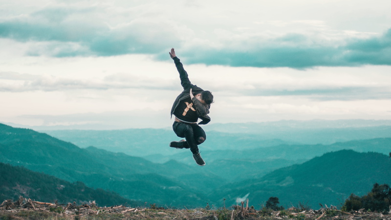 mountain, adventure, outdoors, shirt, dabbing, mountain range, real people, human arm, day, man, mid-air, sky, black, 5K, full length, beauty in nature