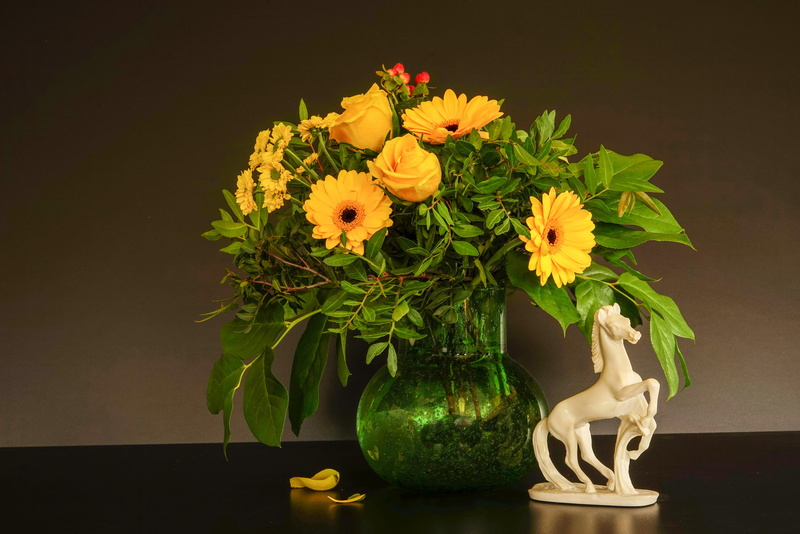 gerbera yellow, vase, ceramic, figurine, flower head, nature, rose yellow, 5K, flower pot, no people, indoors, flower arrangement, horse sculpture, black background