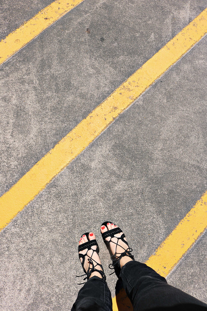 black, cement, person, marking, yellow, pants, shoe, transportation, real people, human body part, symbol, wear, directly above, close-up, one person, red nails