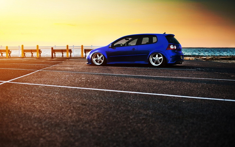 door, blue cars, sky, mode of transportation, dividing line, symbol, outdoors, motor vehicle, blue, road marking, transportation, car, sunset, hatchback