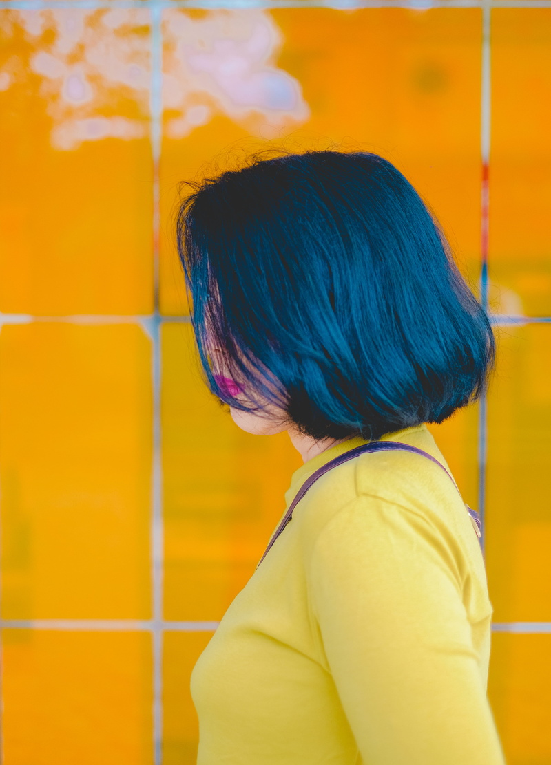 wall - building feature, hairstyle, tiles, woman, headshot, yellow, waist up, pink lips, potrait, casual clothing, sleeved, hair, short hair, standing