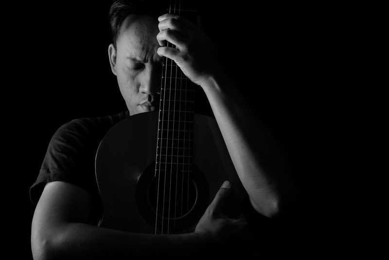 arts culture and entertainment, black background, men, string instrument, photo, black and white, studio shot, acoustic guitar, potrait, plucking an instrument