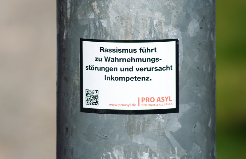 sticker, non-western script, 2K, no people, communication, outdoors, global, script, text, people, sign, flüchtliche, information, human, message, western script