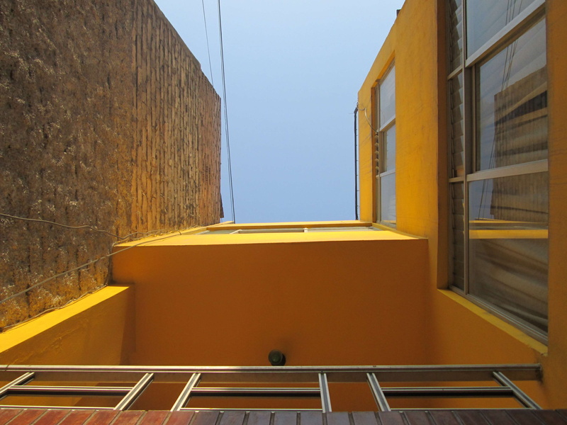 staircase, city, window, day, no people, clear sky, yellow wall, low angle view, sky, nature, directly below, built structure, empty, modern, yellow, sunlight
