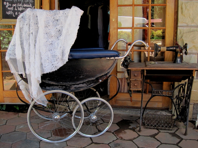 old, no people, building exterior, bicycle, day, pram, beside, building, chair, grey floor paving, table, old fashioned, machine, sewing, white lace covering