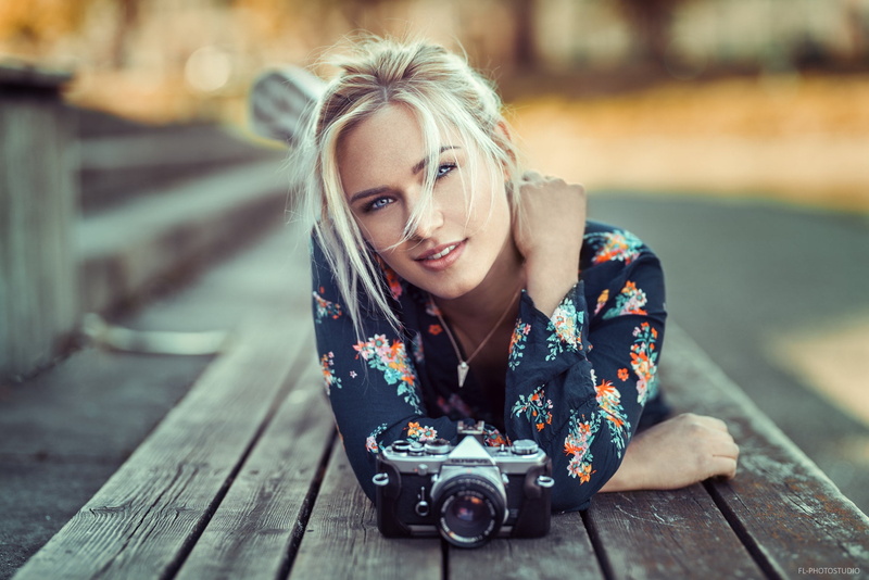 Eva Mikulski, camera, depth of field, smiling, portrait, lying on front, photographer, photo, Lods Franck, 1080P, girl, blonde, open mouth, mouth, model