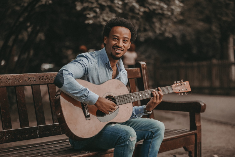 park bench, young men, one person, seat, musician, park, outdoors, string instrument, jeans, artist, playing, adult, three quarter length, skill, gosple