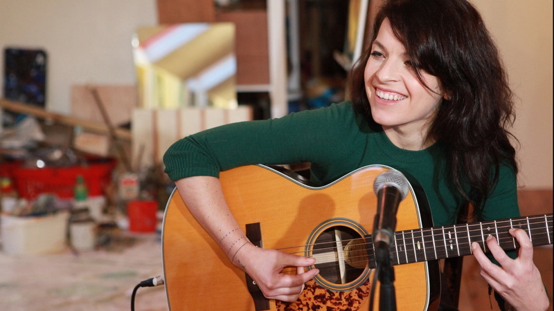sleeved, musical equipment, s, jesca hoop, shirt, one person, guitar, performance, smile, acoustic guitar, hairstyle, hair, long, playing, musician, plucking an instrument
