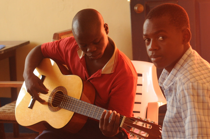 musical Instrument, playing, indoors, string Instrument, performer, young adult, two people, males, polo, guitar lessons, adult, teenager, mozambique, profile view