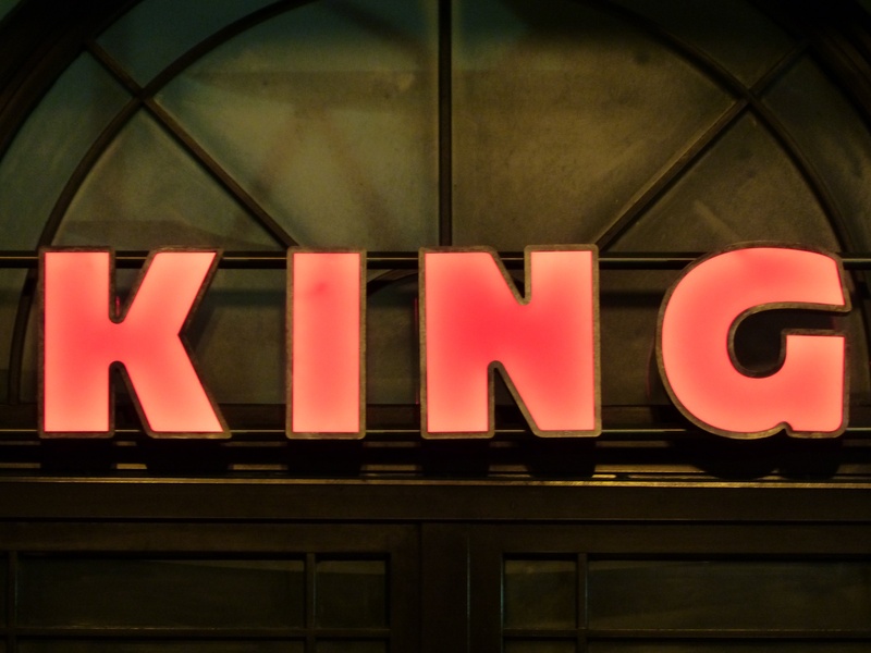 building exterior, low angle view, classic, night, neon sign, western script, sign, illuminated, red, architecture, advertisement, no people, capital letter