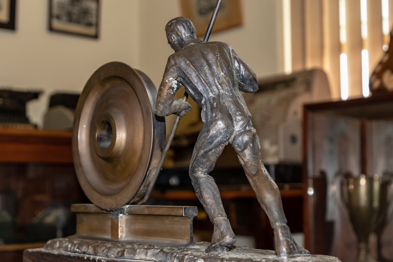 indoors, machine, art and craft, clothing, antique, floor, craft, industry, chime, wheel, male likeness, workshop, hardwood, metal, museum, 5K, human representation