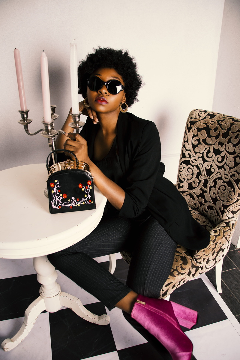 front view, girl, chair, fashion, one person, handbag, lifestyles, sofa, young adult, black, seat, person, room, home interior, sleeved, footwear, tunic