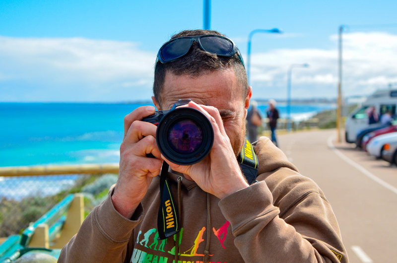 focus on foreground, technology, portrait, sky, activity, ocean, camera - photographic equipment, adult, headshot, holding, leisure activity, water, men
