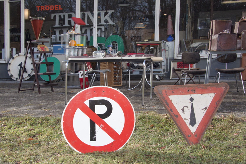 road signs, outdoors, guidance, seat, information sign, chair, luggage, red, junk, road sign, used, building exterior, road warning sign, architecture