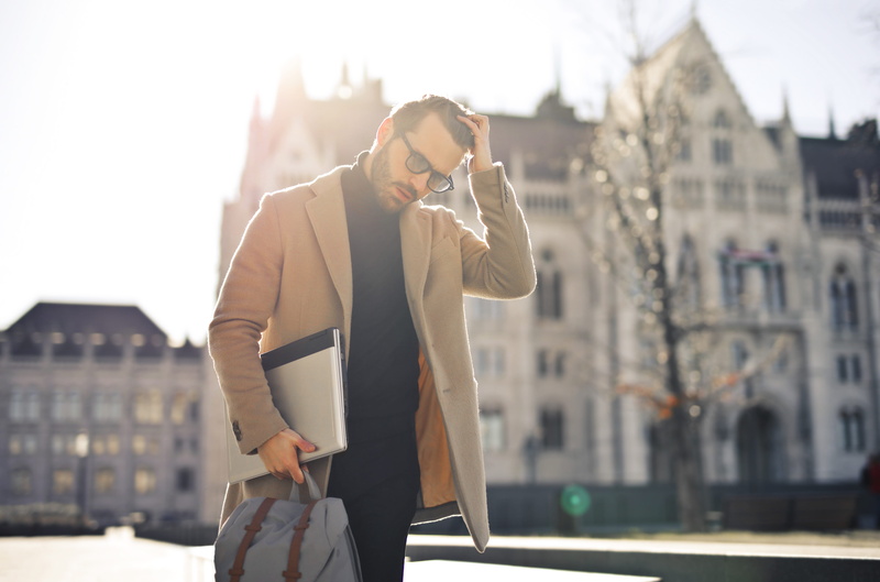 black pants, handsome, hairstyle, 5K, coat, eyewear, building exterior, electronics, turtleneck, city, facial expression, architecture, one person, model
