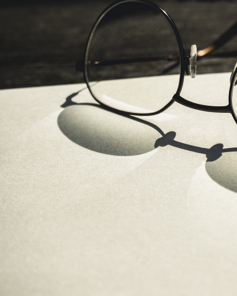 shadow, accessories, electronics, glass - material, eyeglasses, no people, table, still life, focus on foreground, page, indoors, desk, personal accessory