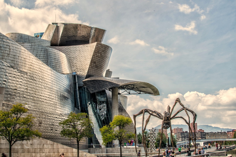 office building exterior, outdoors, guggenheim, built structure, travel destinations, cloud - sky, building exterior, sky, history, museums, low angle view