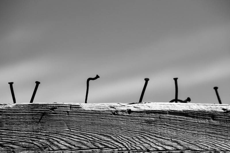 focus on foreground, nail, wooden post, low angle view, minimalism, fence, boundary, pattern, nature, outdoors, architecture, textured, barrier, side by side
