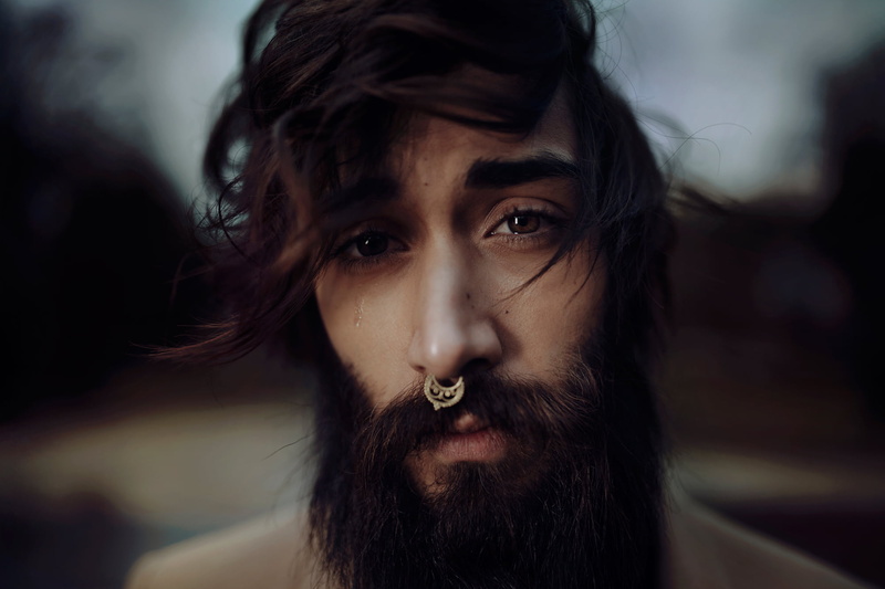 beard, headshot, contemplation, portrait, outdoors, looking at camera, mustache, person, brown hair, individuality, piercing, black hair, focus on foreground