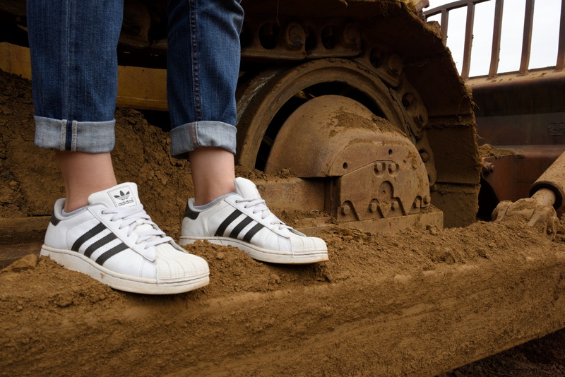 sneakers, human leg, real people, day, adidas, casual clothing, levis, close up, human limb, lifestyles, dirt, 3 bands, sitting, jeans, caterpilar, limb