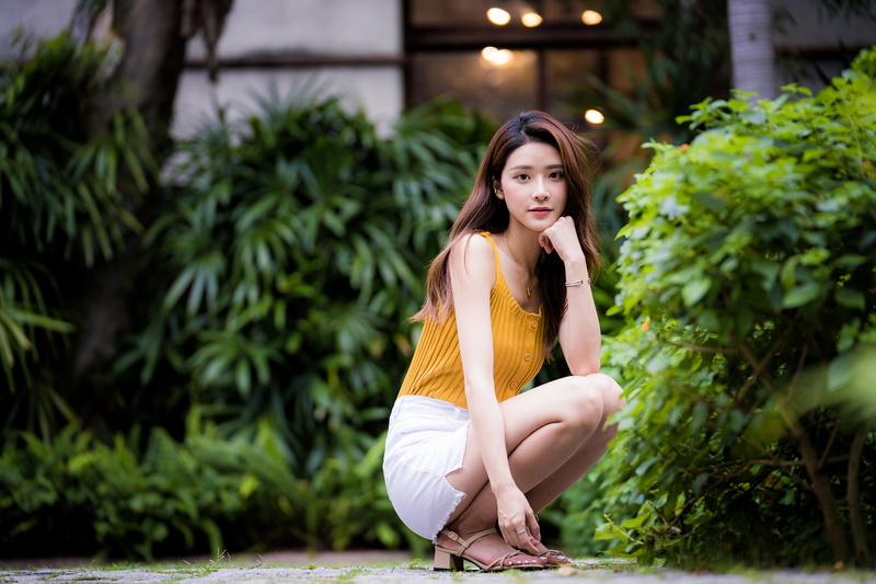 yellow shirt, looking at viewer, Asian, trees, squatting, model, barefoot sandal, brunette, depth of field, women, 4K, long hair, Bushes, white skirt