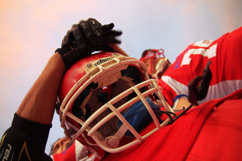 standing, helmet, holding, red, uniform, player, men, adult, midsection, incidental people, outdoors, teamwork, football, group of people, human body part