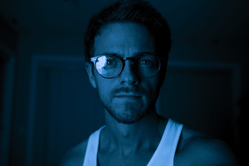 framed, front view, guy, black background, portrait, 2K, person, headshot, beard, room, indoors, glasses, adult, focus on foreground, wearing, men, wayfarer