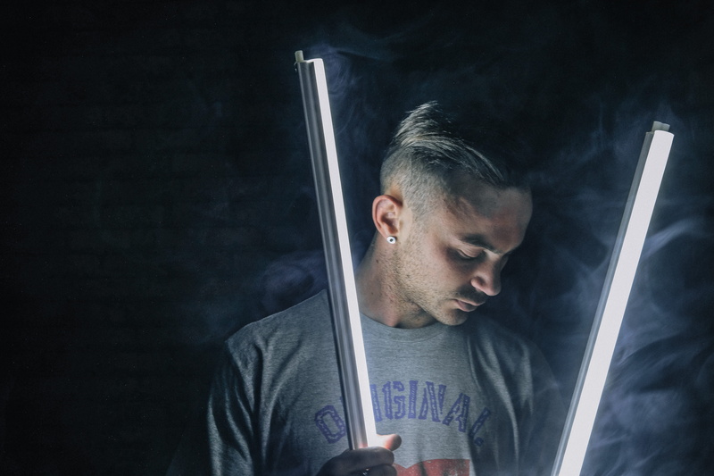 black background, copy space, studio shot, earring, lamps, one person, smoke, male, looking down, indoors, closeup, holding, front view, person, studio
