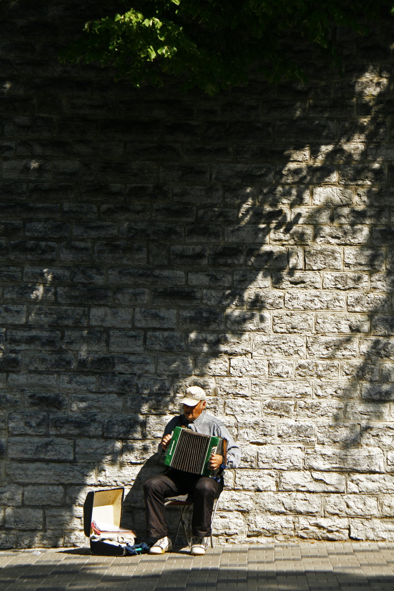 shirt, staircase, senior adult, case, wall, built structure, elderly, daytime, outdoors, instrument, 4K, near, sunlight, stone, person, building exterior