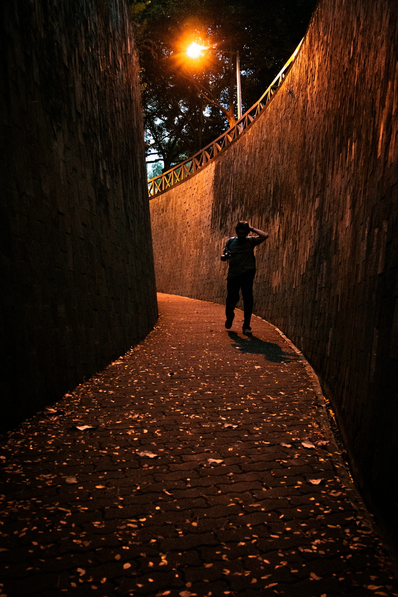 full length, illuminated, one person, built structure, walking, footpath, night, wall - building feature, maze, alley, leisure activity, man, rear view