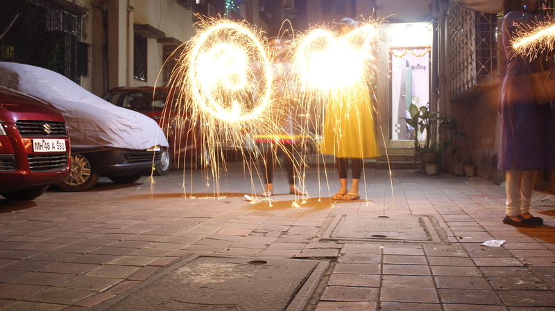 men, motor vehicle, night, paving stone, sparkle, blurred motion, one person, city, illuminated, outdoors, firework, women, firework - man made object