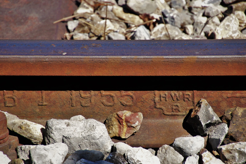 textured, day, digits, pebble, steel, sunlight, splint, text, stack, gravel, outdoors, figure, rail transportation, rust, focus on foreground, high angle view