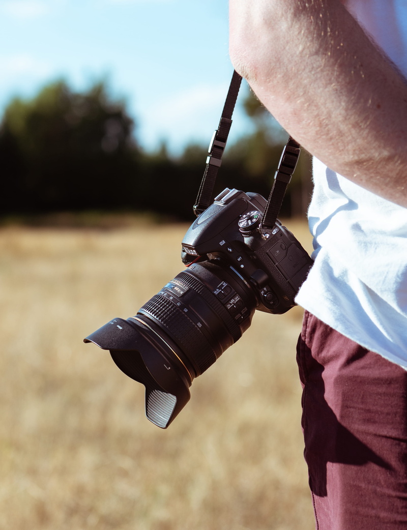 person, tech, bourne woods, photography themes, technology, holding, style, human hand, strap, sunlight, camera, male, real people, man, grass, finger