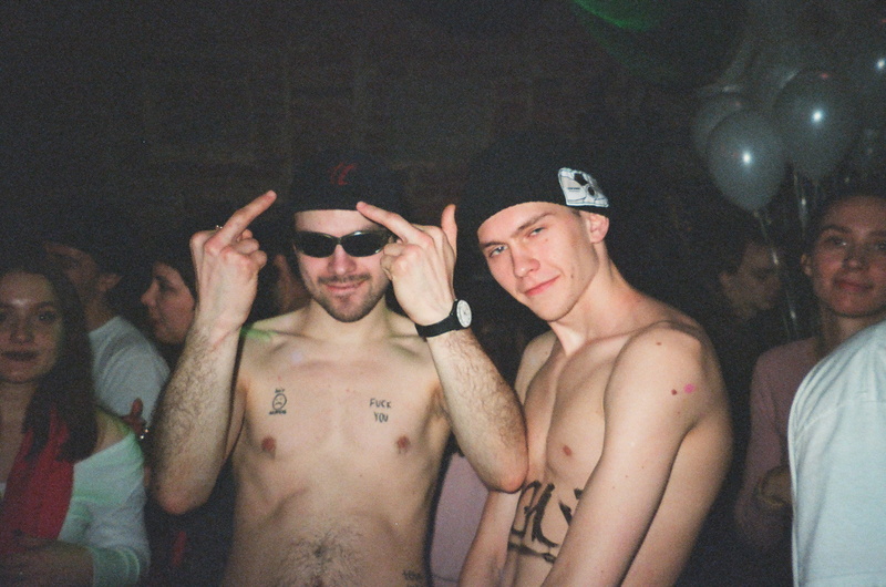 men, looking at camera, night, crowd, lifestyles, waist up, enjoyment, real people, night time, white, young men, young adult, tattoo, chest, group, facial expression
