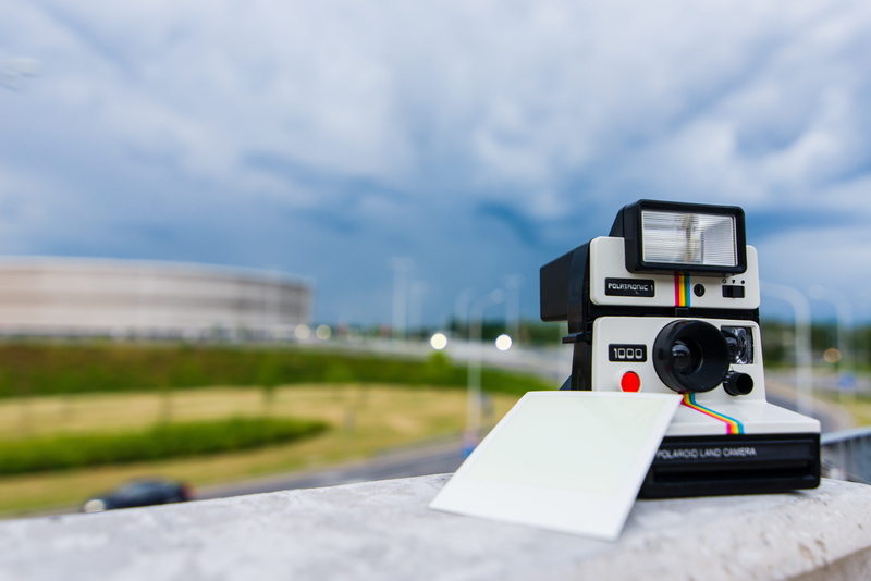 instant camera, land, outdoors, day, focus on foreground, field, no people, equipment, sky, black, technology, communication, photography themes, paper
