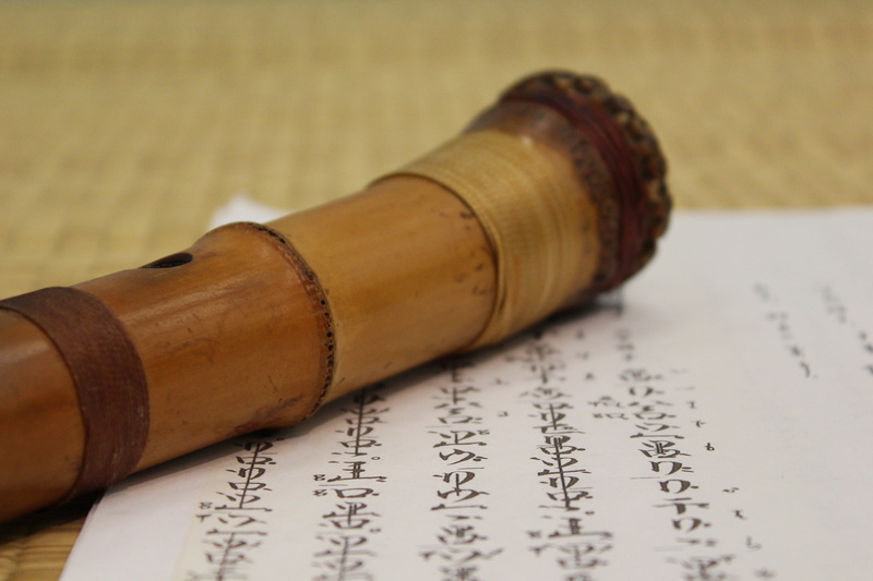 close-up, music, paper, wooden, indoors, calligraphy, document, lying down, wind, japanese flute, writing, mat, instrument, brown, text, single object