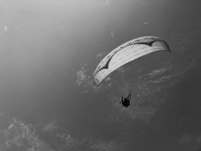 paragliding, unrecognizable person, aircraft, helicopter, gliding, person, bird, day, dance pose, transportation, grayscale, vehicle, dance, photo, mid-air