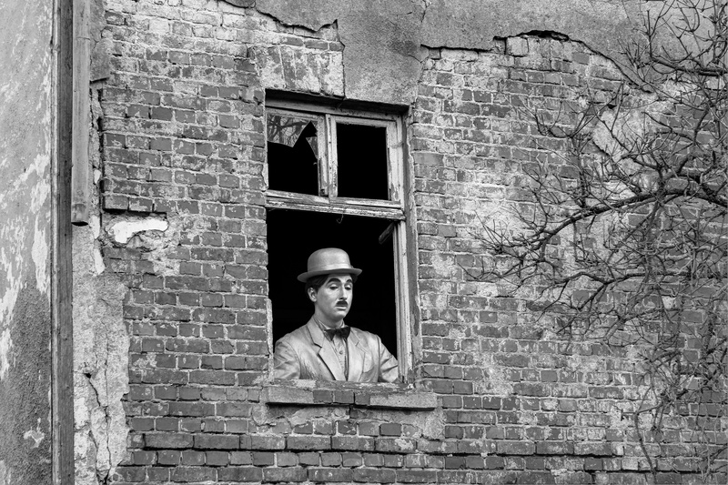 male likeness, art and craft, building exterior, chaplin, outdoors, black, brick, built structure, architecture, black white, charlie, clown, fantasy, old