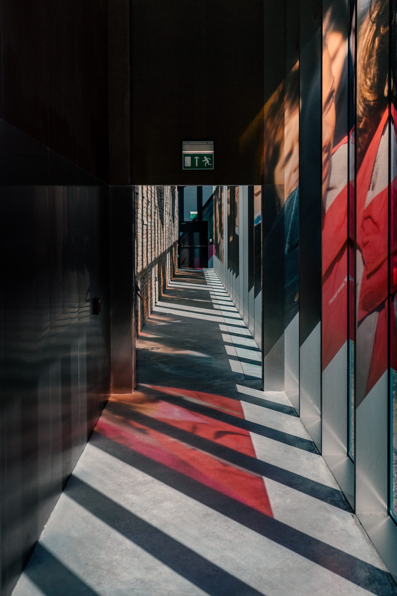 light, painted, direction, indoors, diagonal, architecture, wall, arcade, empty, day, transportation, architecure, door, red, gray, exit, text, grey, ceiling